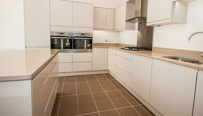 A kitchen with white cabinets and tile flooring.